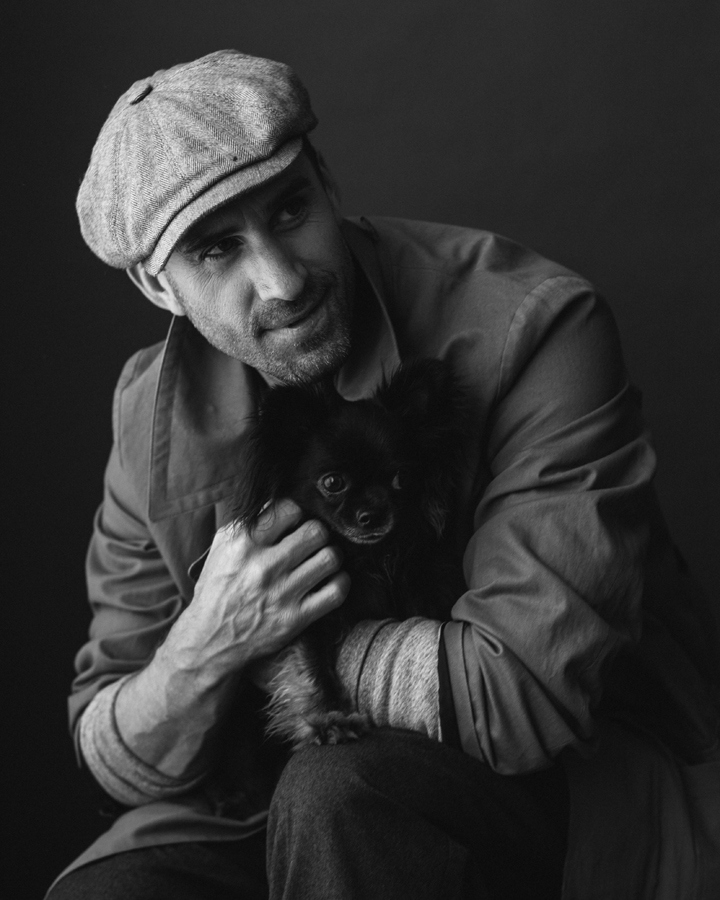Photo of Actor Joseph Fiennes, from Handmaid's Tale photographed in studio in black and white. Wearing APC, Billy Reid. Actor hold black chihuahua named Vader.